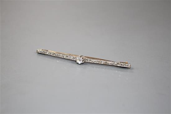 A 1920s yellow and white metal, diamond bar brooch, with central old cut diamond and millegrain set rose cut diamonds,